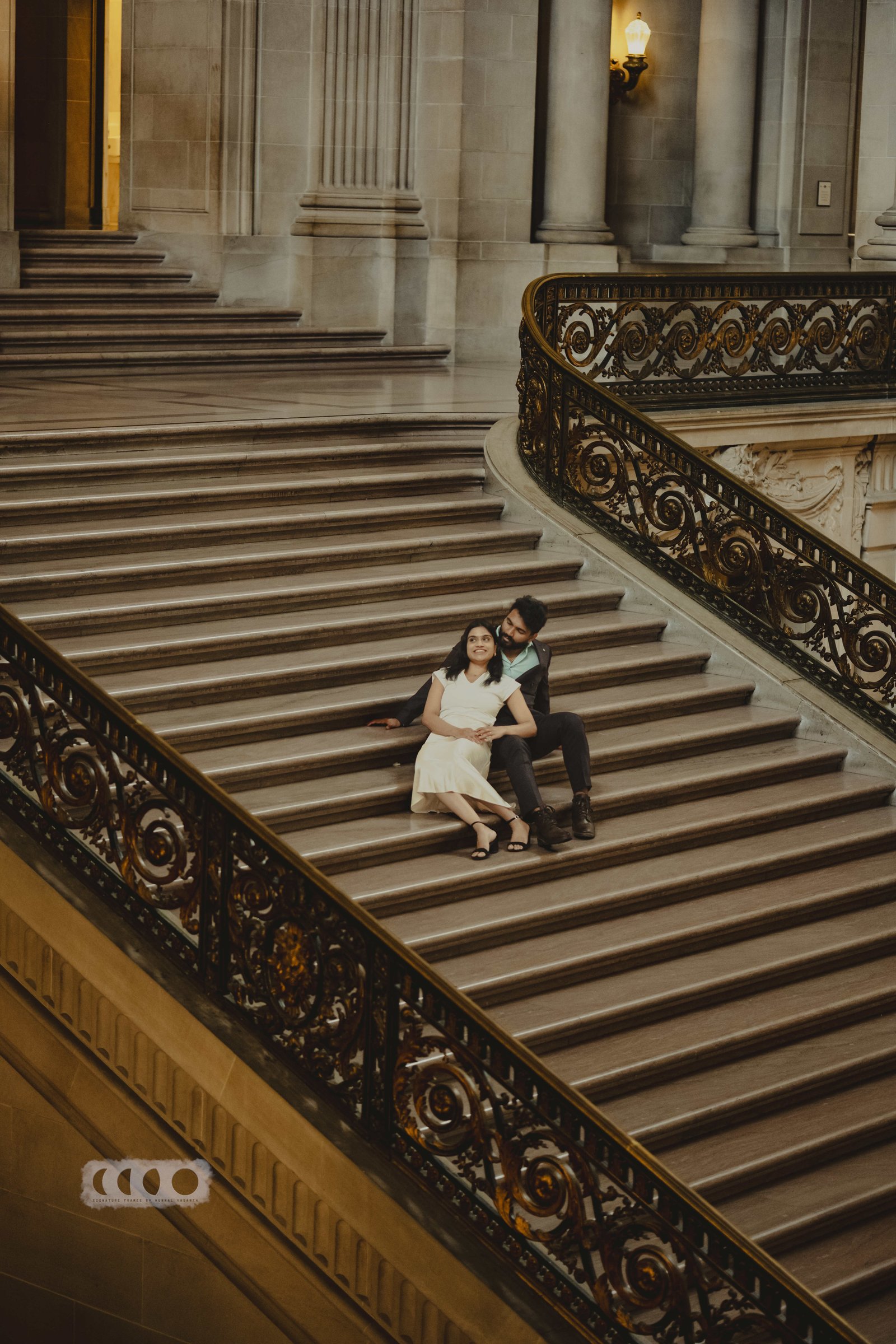 Sid and Janavi seated on a sweeping staircase